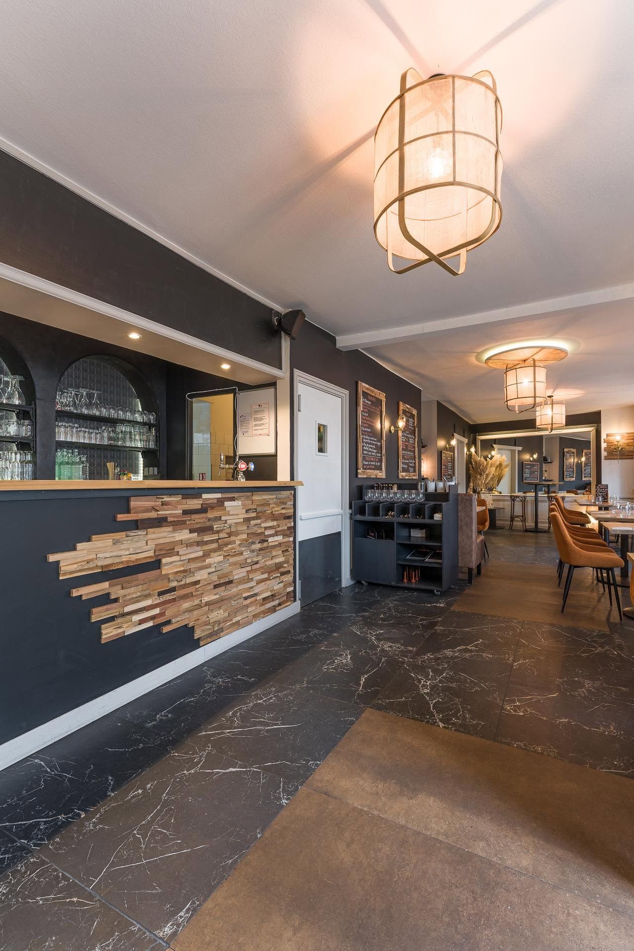 Couloir d'hôtel moderne avec murs, luminaires suspendus à l'ambiance chaleureuse et comptoir d'enregistrement orné de briques.