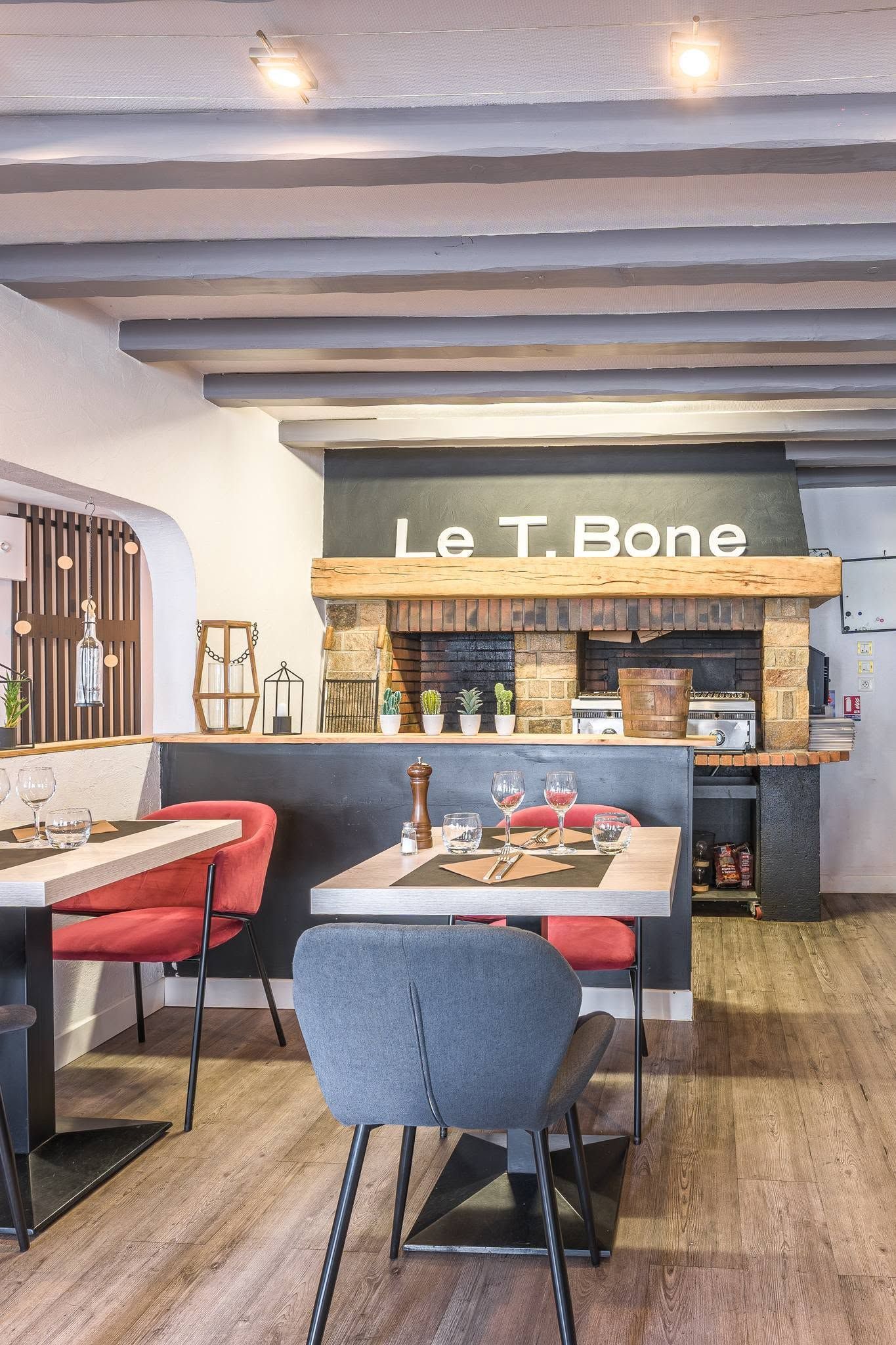 Salle à manger moderne avec chaises, banquettes et bar en pierre portant l'inscription Le T Bone.