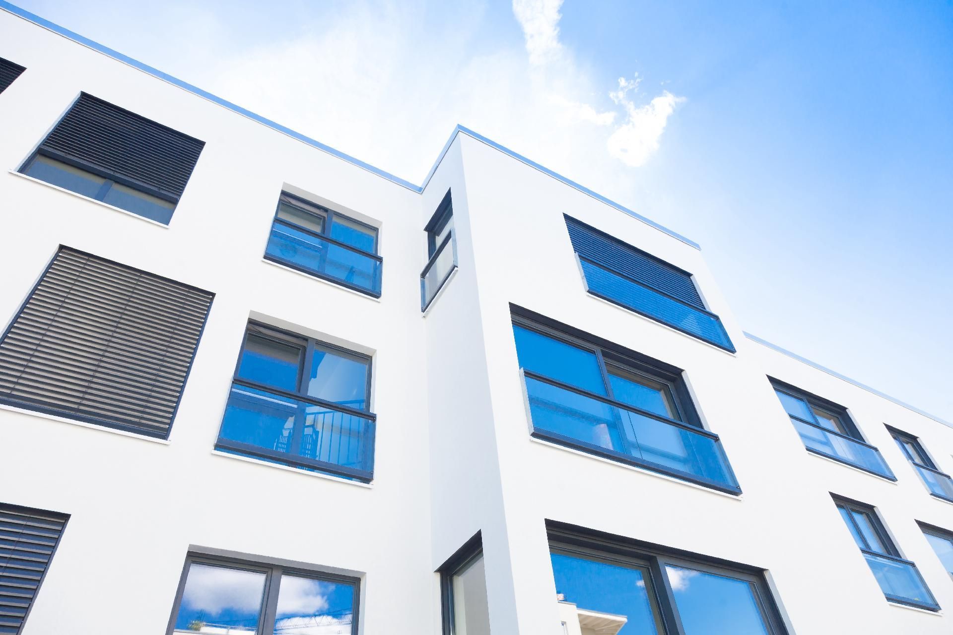 Modernes weißes Gebäude Modernes weißes Gebäude mit blau getönten Fenstern, von unten vor klarem Himmel betrachtet