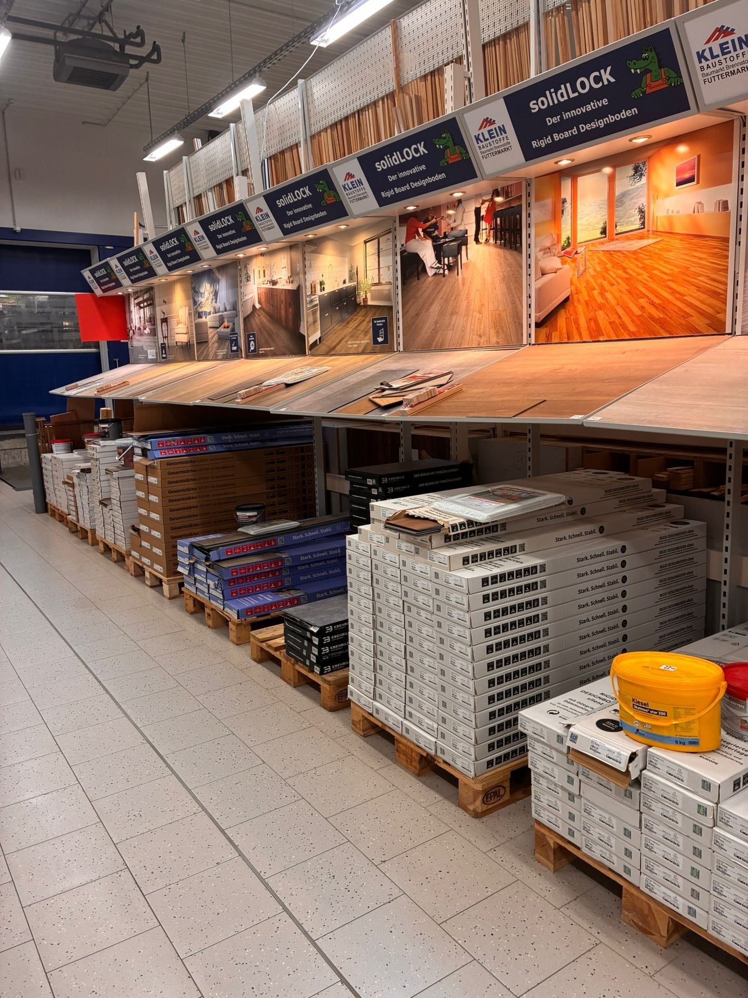 Eine Reihe von Fliesen- und Bodenbelagsmustern ist in einem Ladengang unter hellem Deckenlicht ausgestellt.