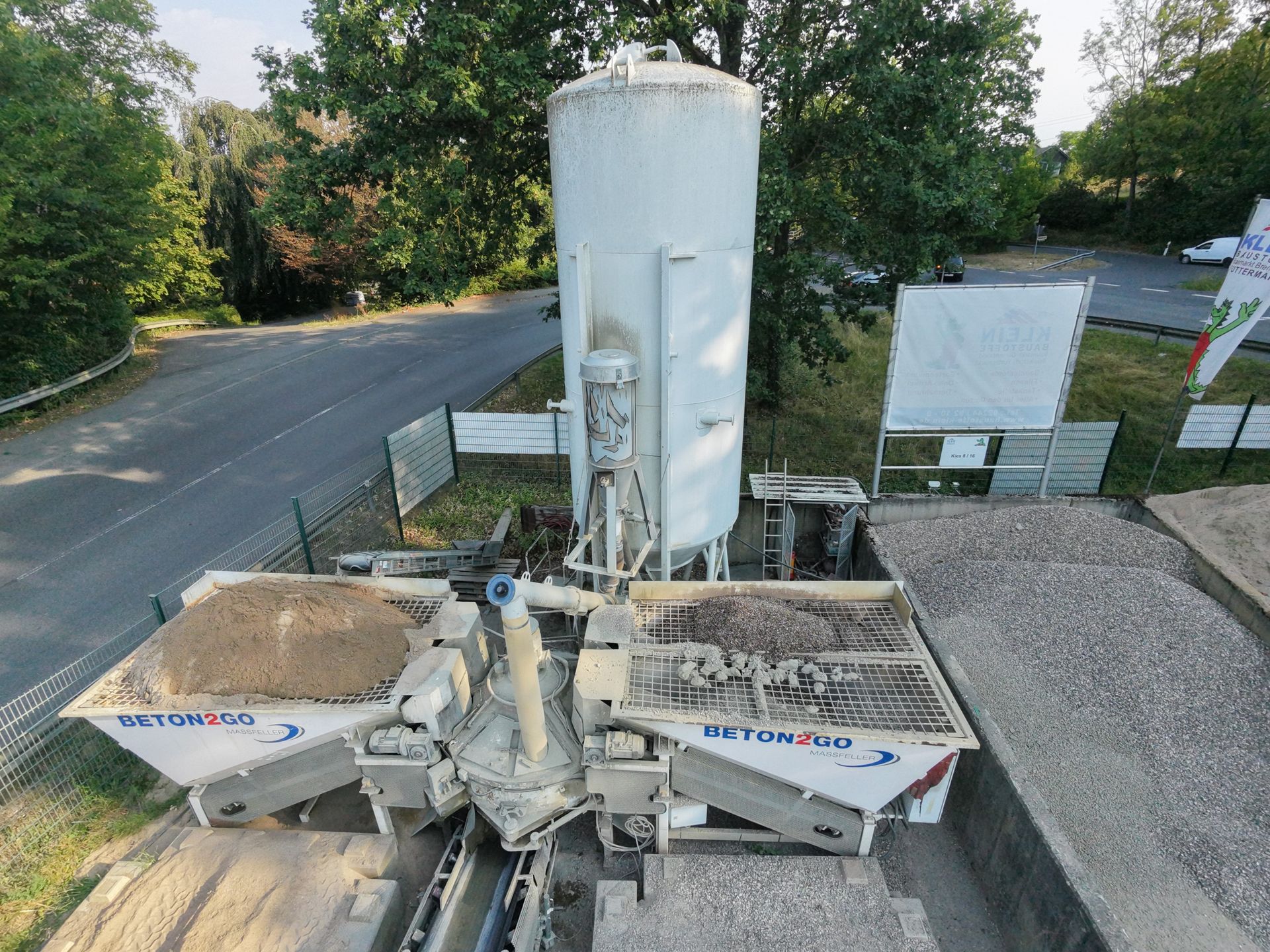 Betonmischanlage Betonmischanlage mit hohem weißen Silo und zwei Mischbehältern neben einer Straße.