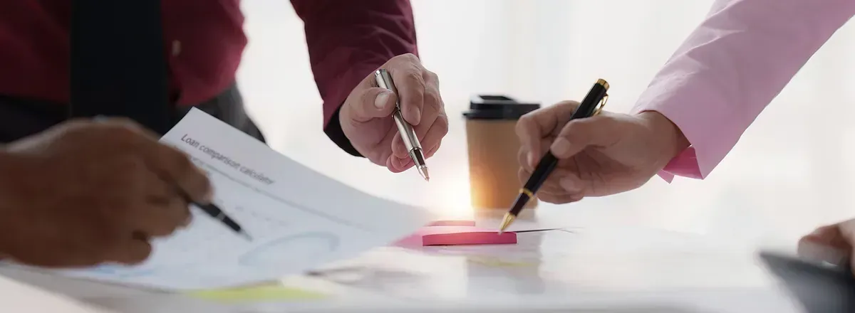 Un grupo de personas está sentada en una mesa firmando un documento.