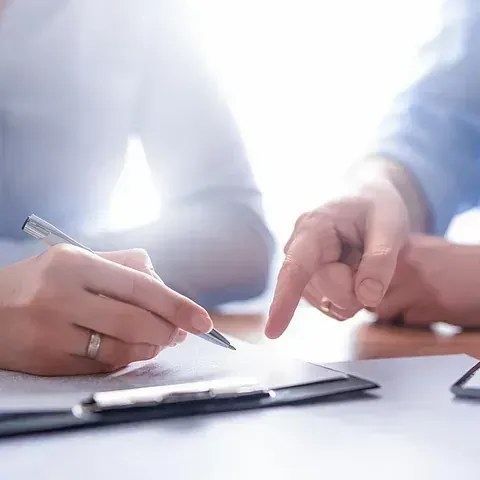 Un hombre y una mujer están sentados en una mesa firmando un documento.