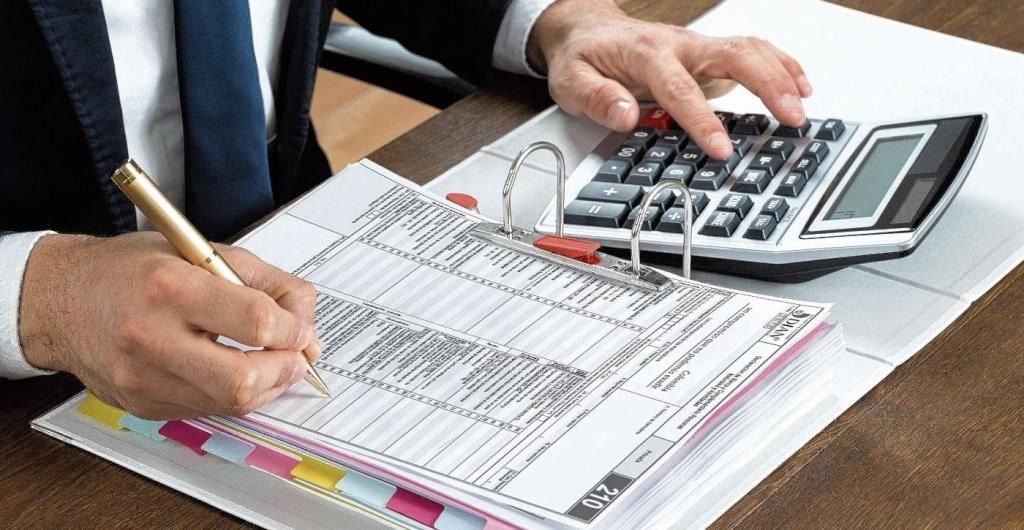 Un hombre está usando una calculadora y escribiendo en un cuaderno.