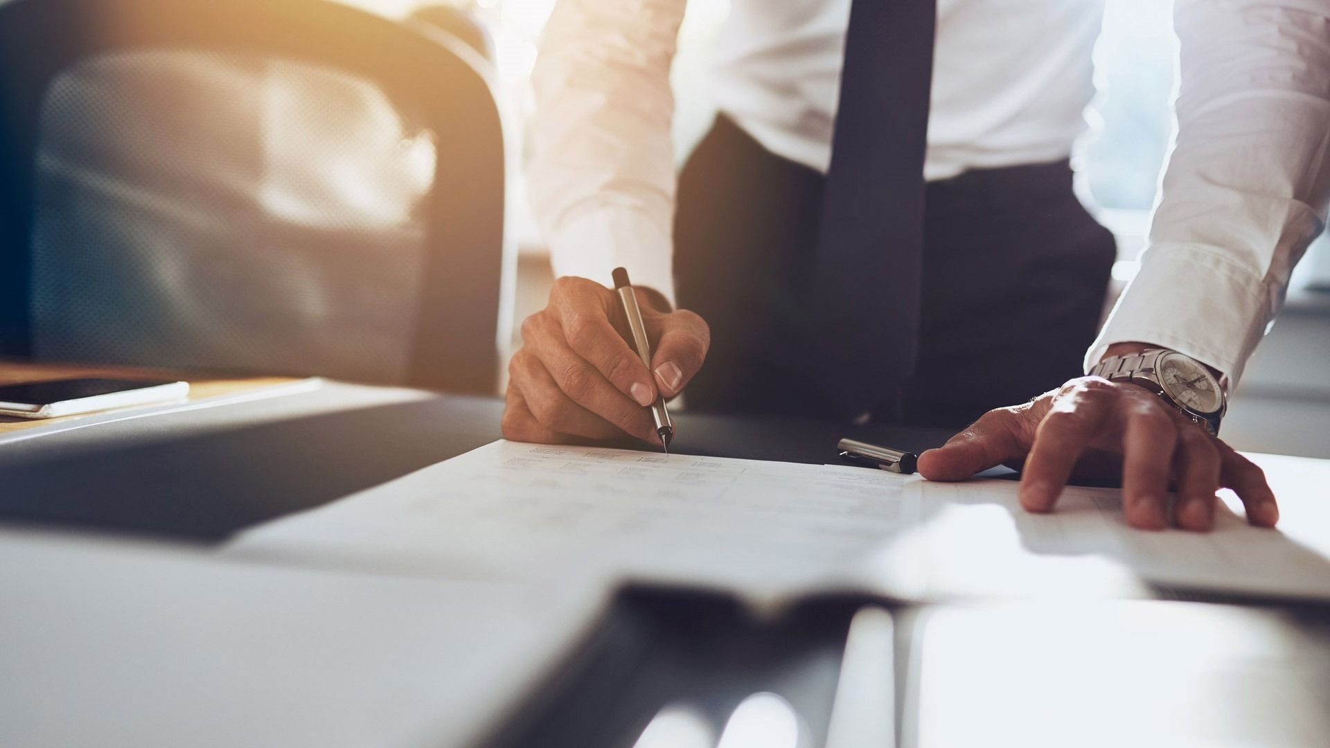 Un hombre con traje y corbata está firmando un documento.