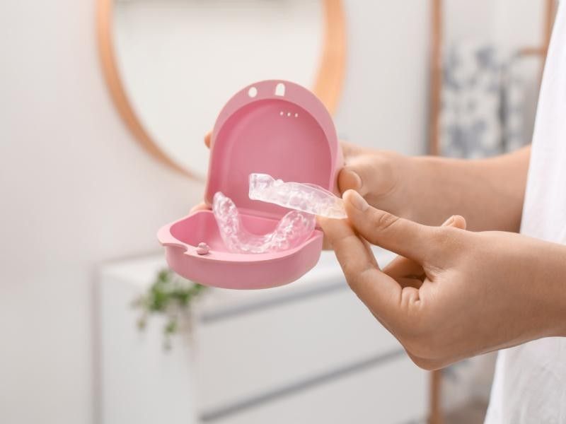 Hände öffnen eine rosa Pillendose, aus der Wasser aus einer Tablette im Inneren ausläuft.