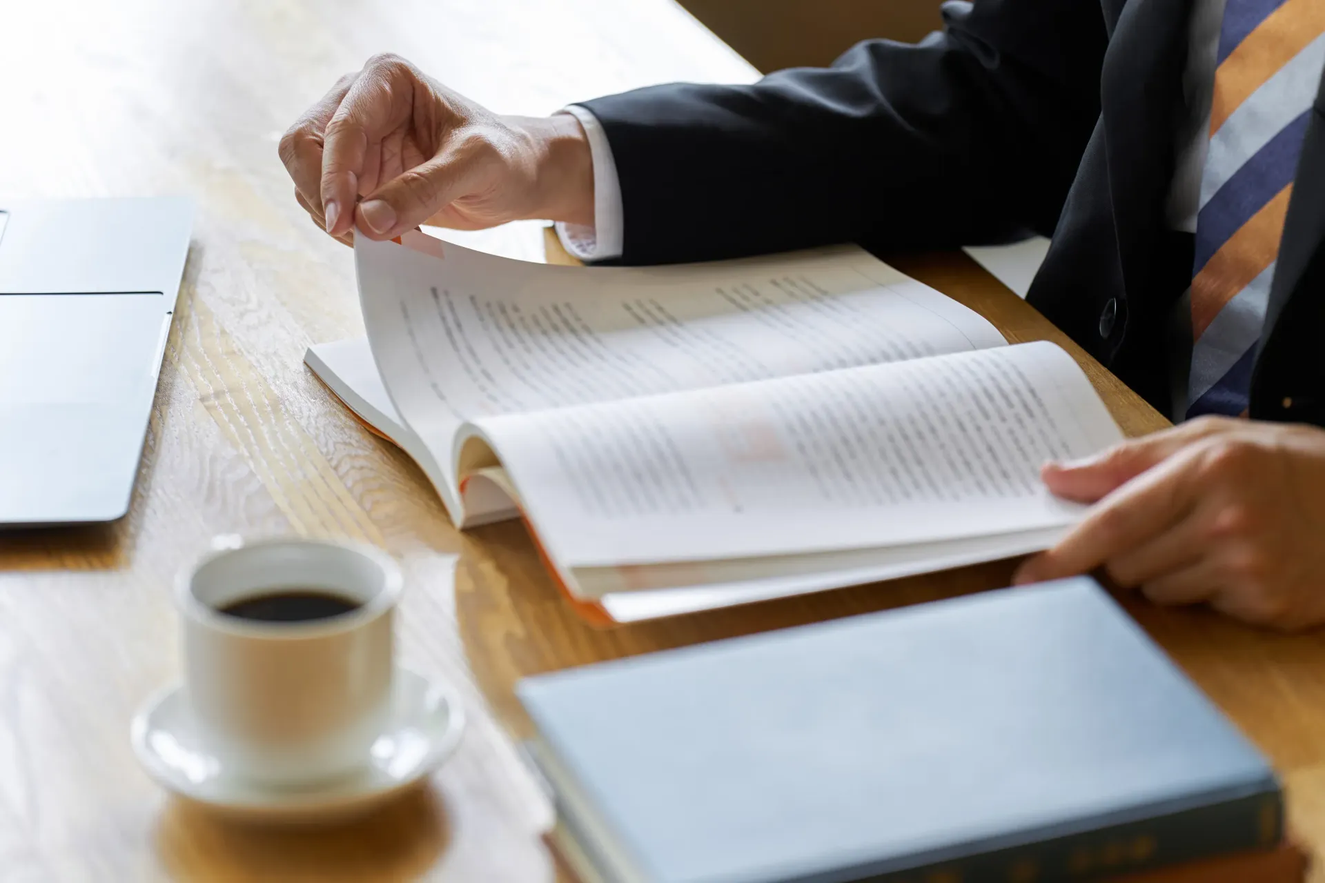 Un hombre con traje y corbata está sentado en una mesa leyendo un libro.