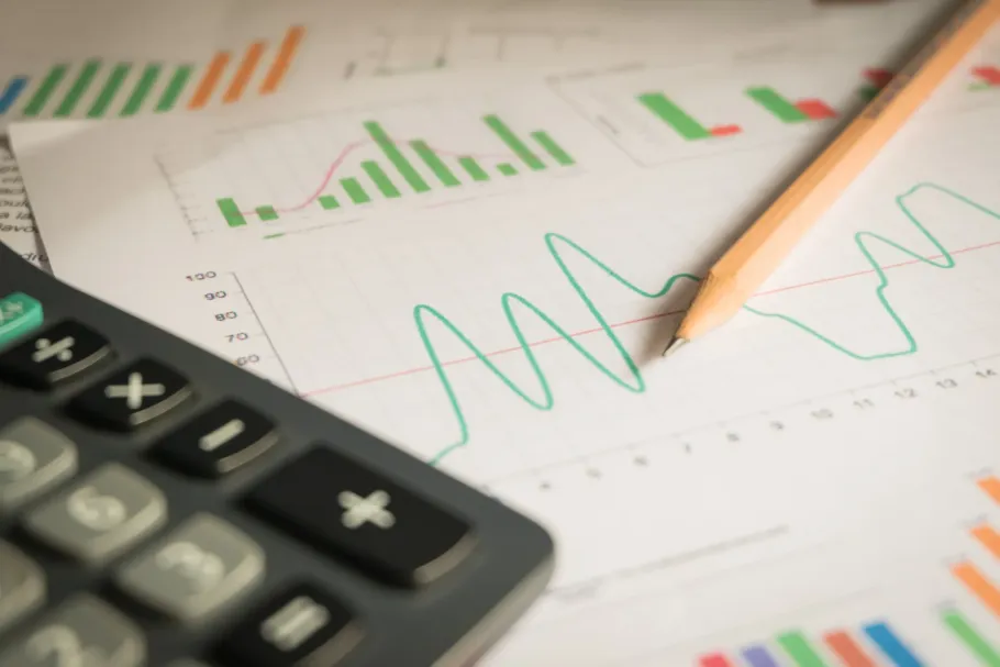 Una calculadora está encima de un gráfico con un lápiz.