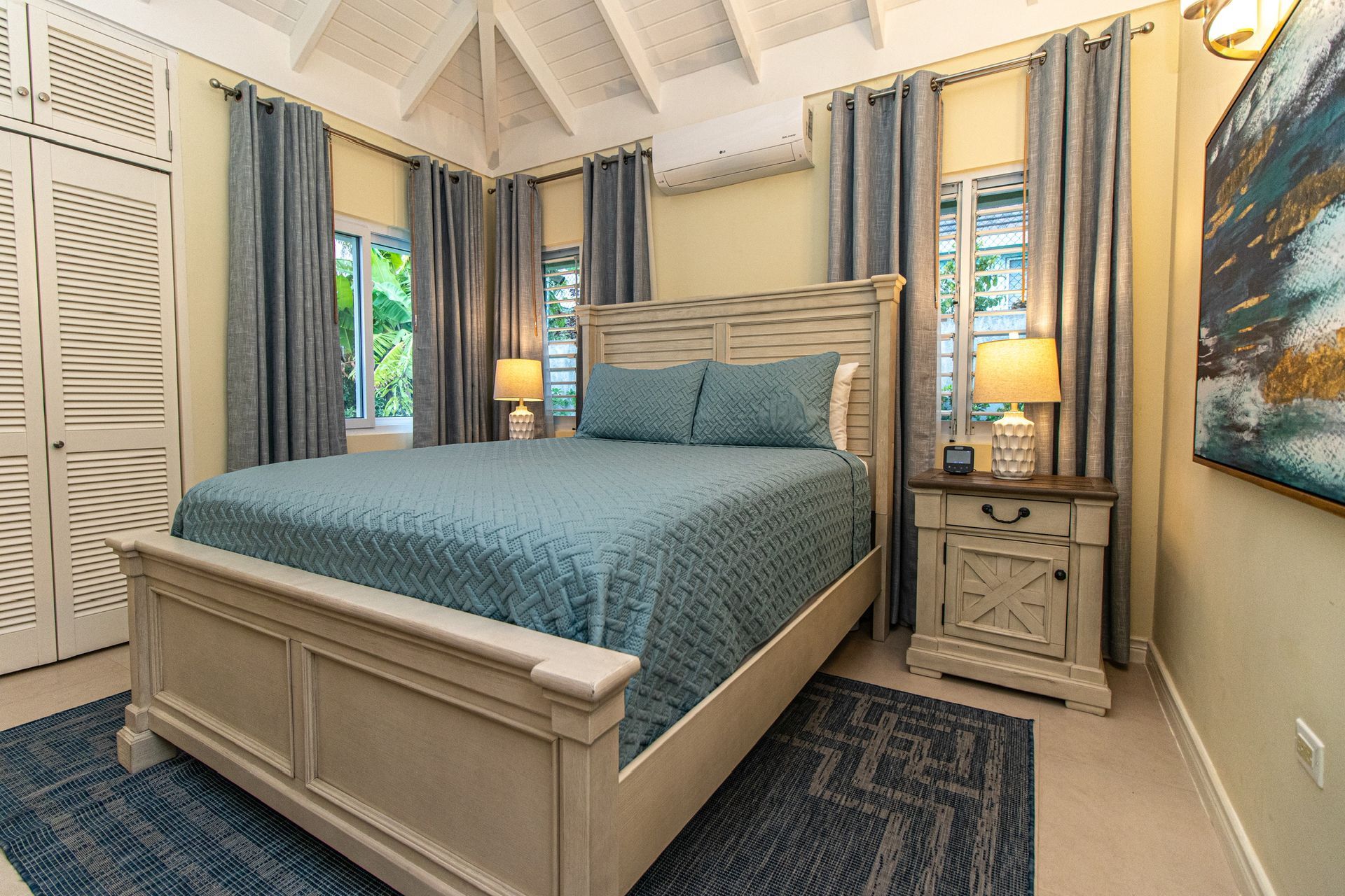 A bedroom with a king size bed , nightstand , lamps and curtains.