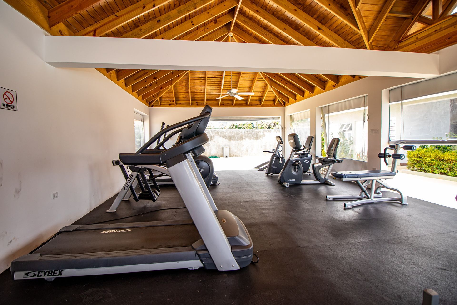A gym with treadmills and exercise bikes under a wooden roof