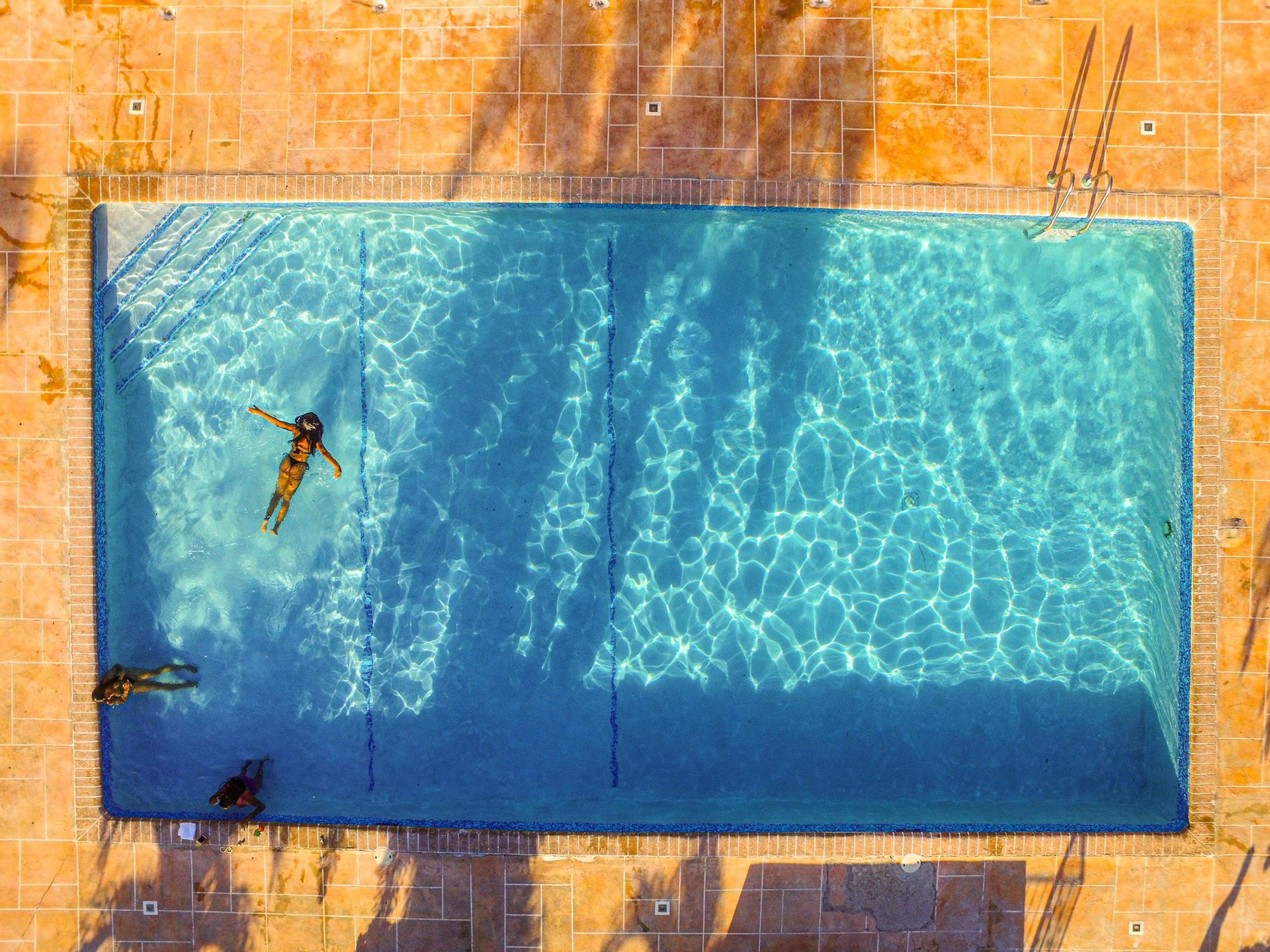 An aerial view of a swimming pool with people swimming in it.