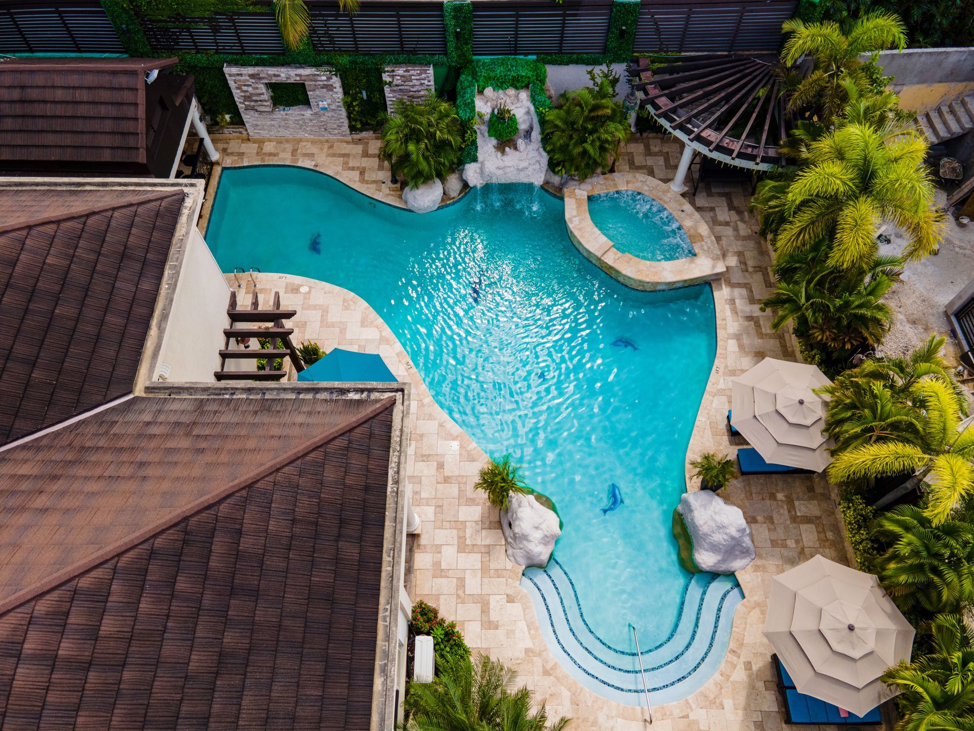 An aerial view of a large swimming pool surrounded by trees and umbrellas.