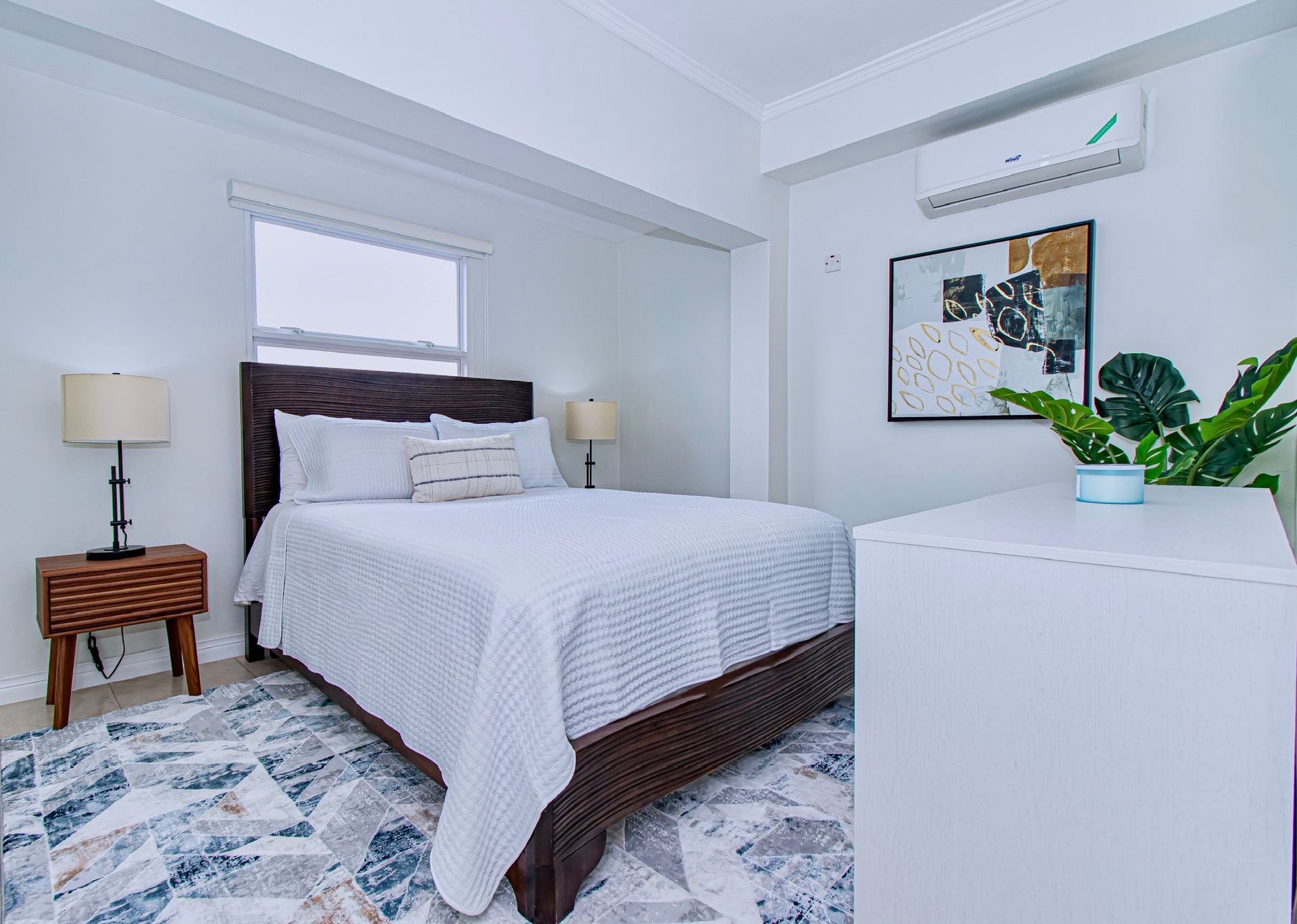 A bedroom with a bed , nightstand , lamp and dresser.