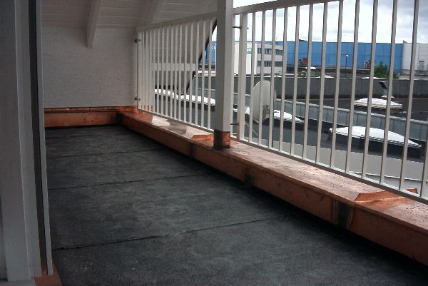 Ein leerer Balkon mit weißem Geländer und Blick auf die Stadt