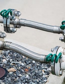 Tuyaux métalliques flexibles avec brides et ressorts verts.