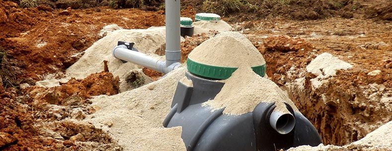 Installation d'une fosse septique dans une tranchée, recouverte de sable.