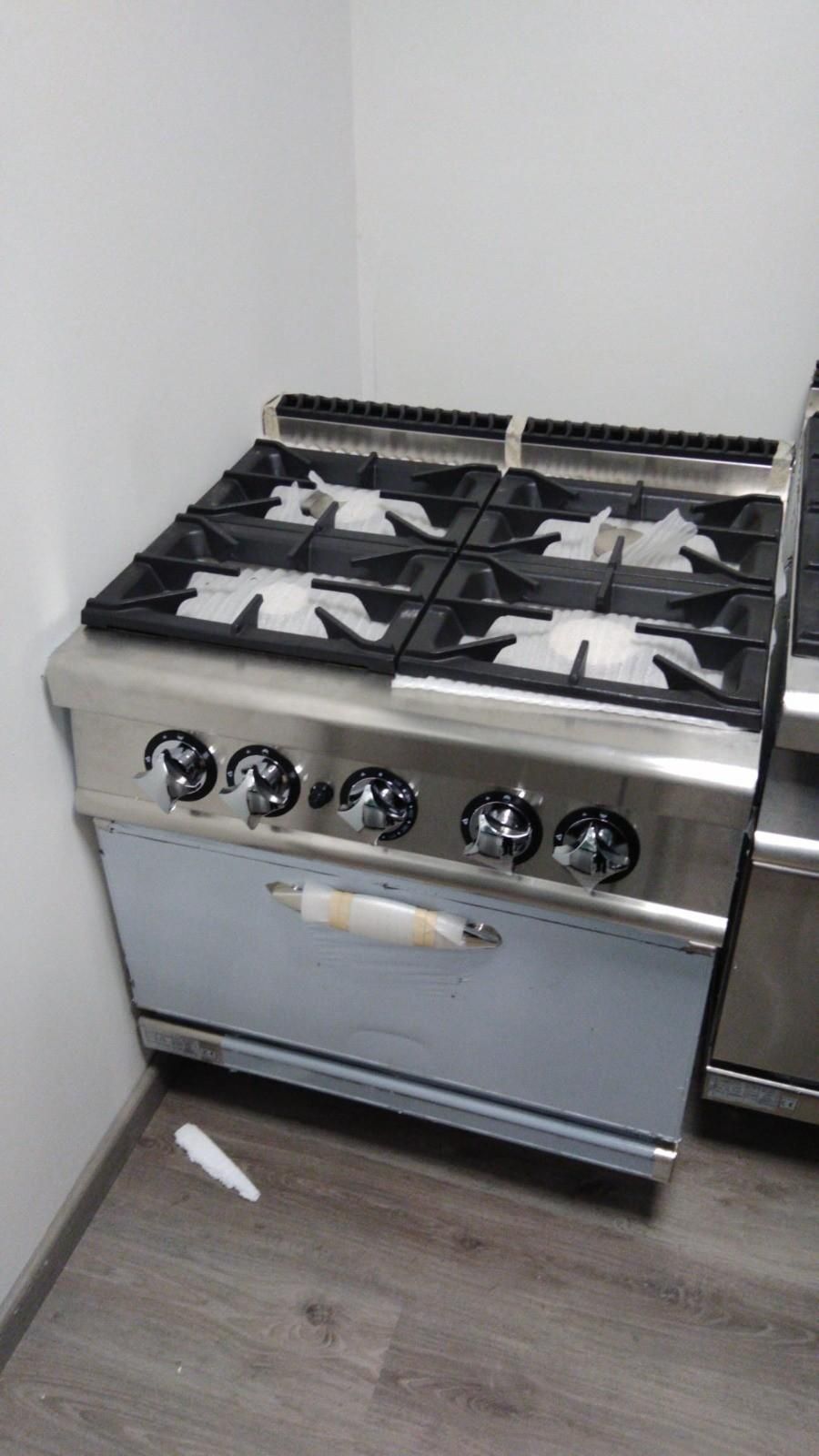 Cocina de gas de acero inoxidable en un rincón de la cocina, con quemadores y mandos de control negros.