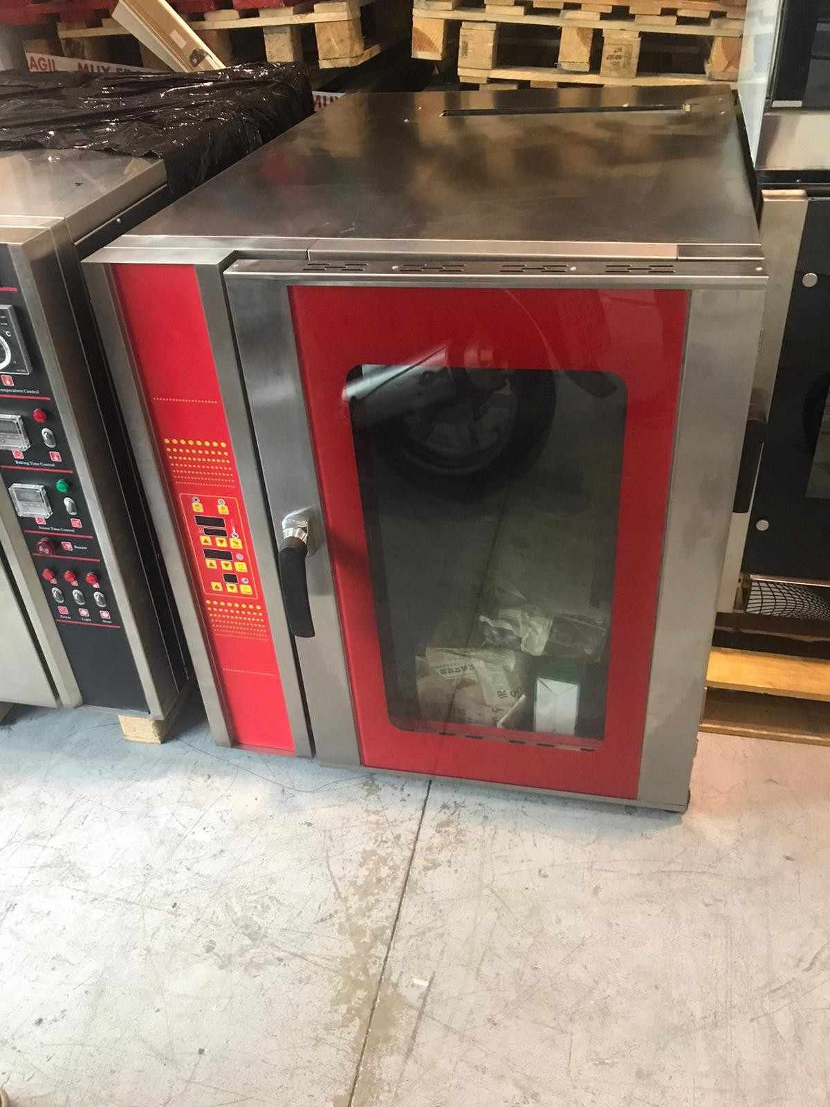 Horno comercial rojo con ventana de visualización negra y panel de control en un taller o área de cocina.