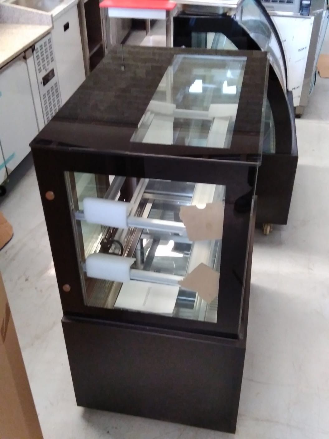 Vitrina de cristal negro con estantes espejados en una habitación, vista desde un ángulo