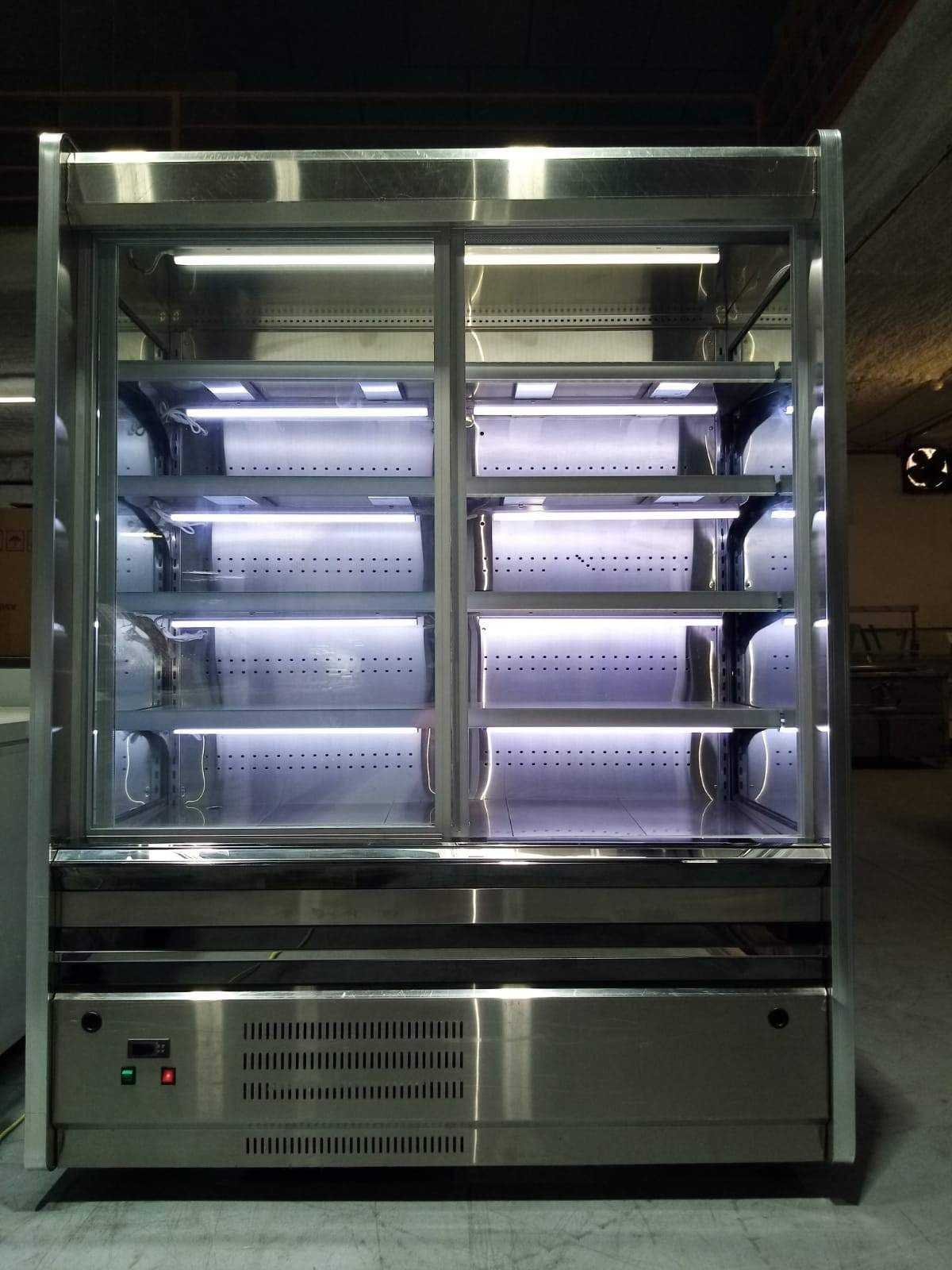 Vitrina de cristal iluminada con estantes metálicos vacíos en un ambiente interior oscuro.