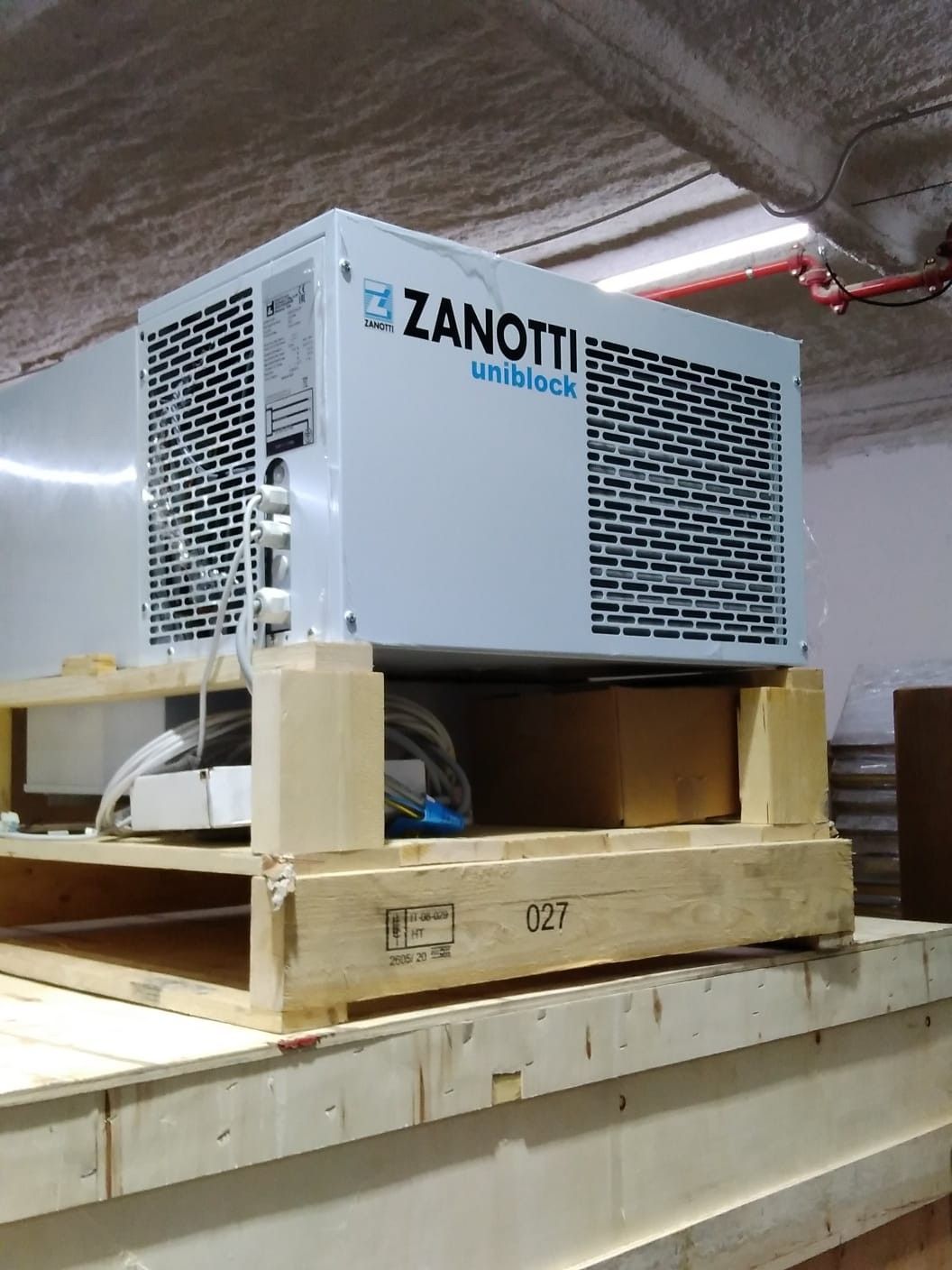 Unidad de refrigeración Zanotti sobre un palé de madera en una cámara frigorífica industrial.