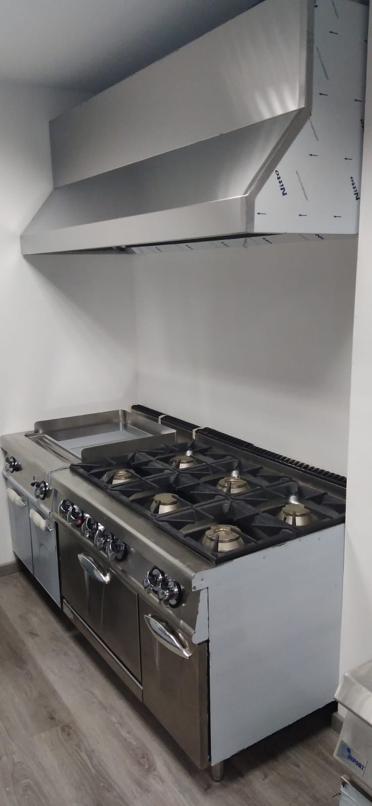 Cocina moderna de acero inoxidable con cocina de gas profesional y gran campana extractora metálica.