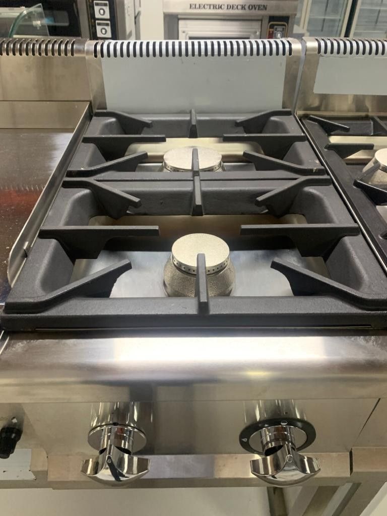 Placa de gas de acero inoxidable con cuatro quemadores y mandos de control integrada en la encimera de la cocina.