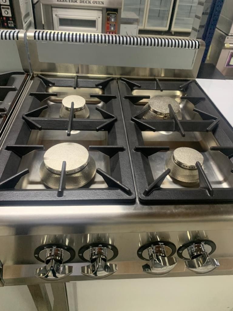 Cocina con horno de gas de acero inoxidable, cuatro quemadores y mandos de control frontales.