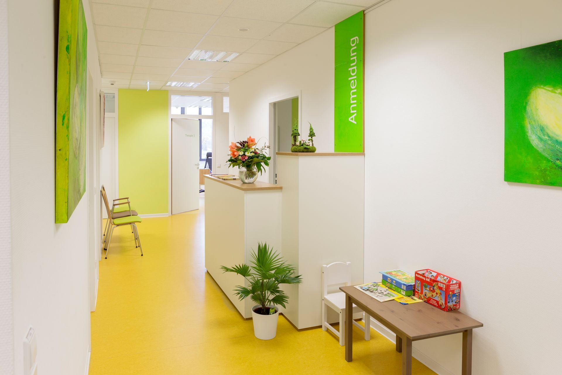 Ein modernes Bürogebäude mit großen Fensterflächen vor dem sich Blumenbeete und Bäume befinden