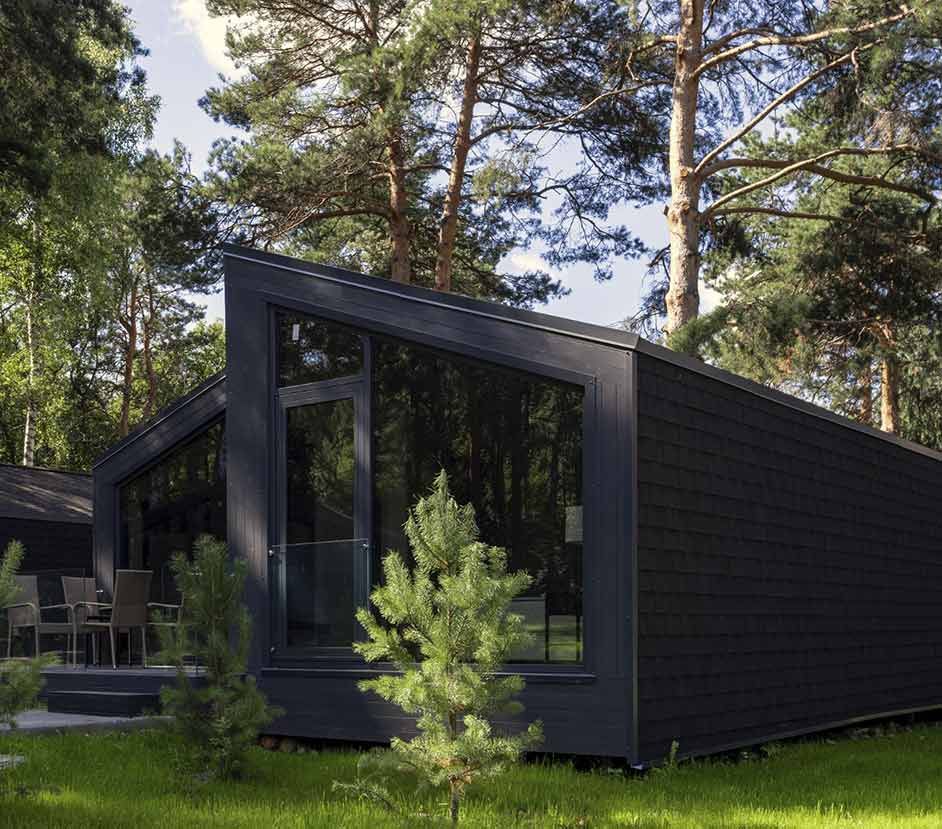 Una hilera de pequeñas casas de madera con techo negro en un bosque.