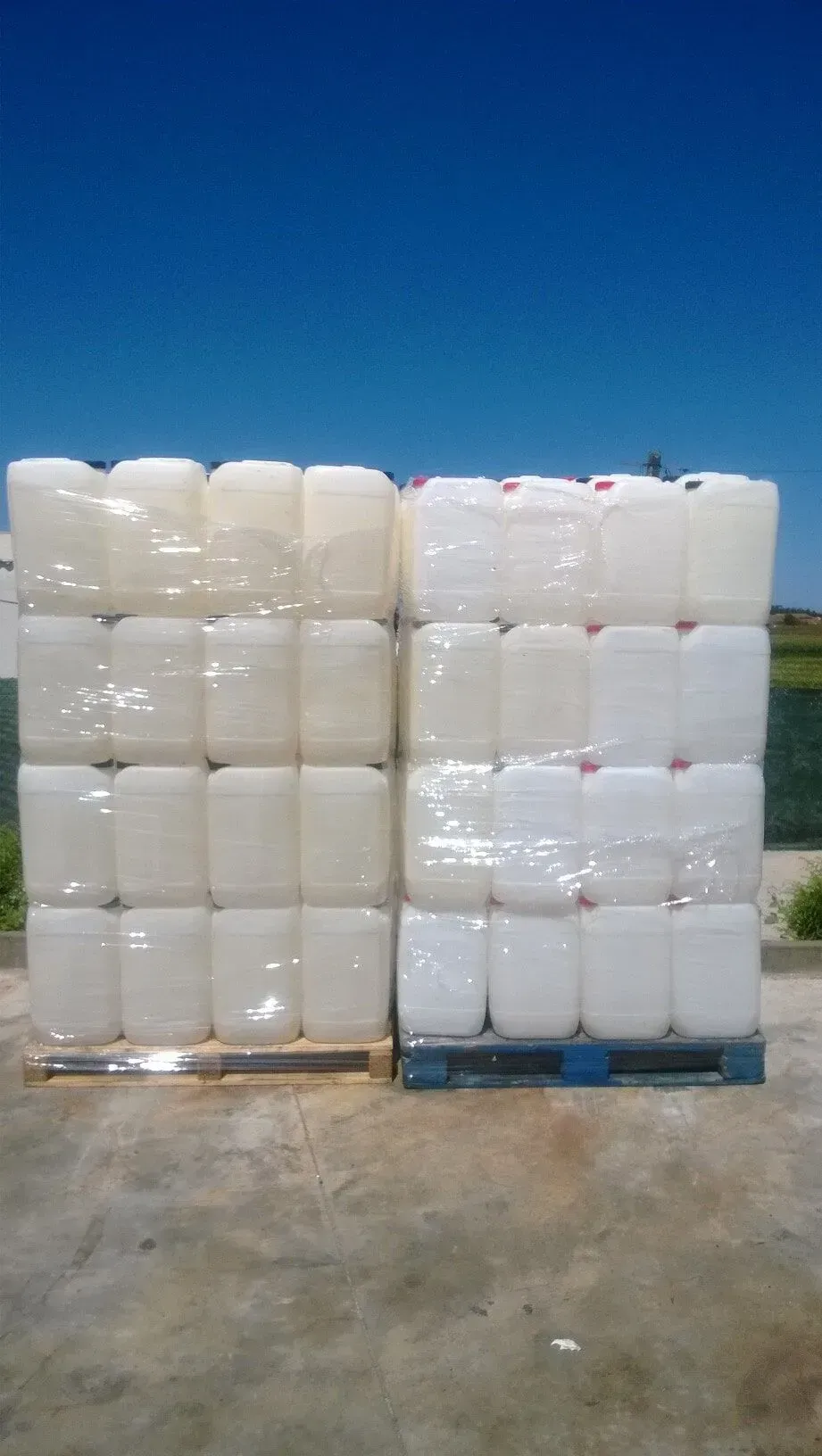 Duas pilhas de barris de plástico branco em cima de um palete de madeira.