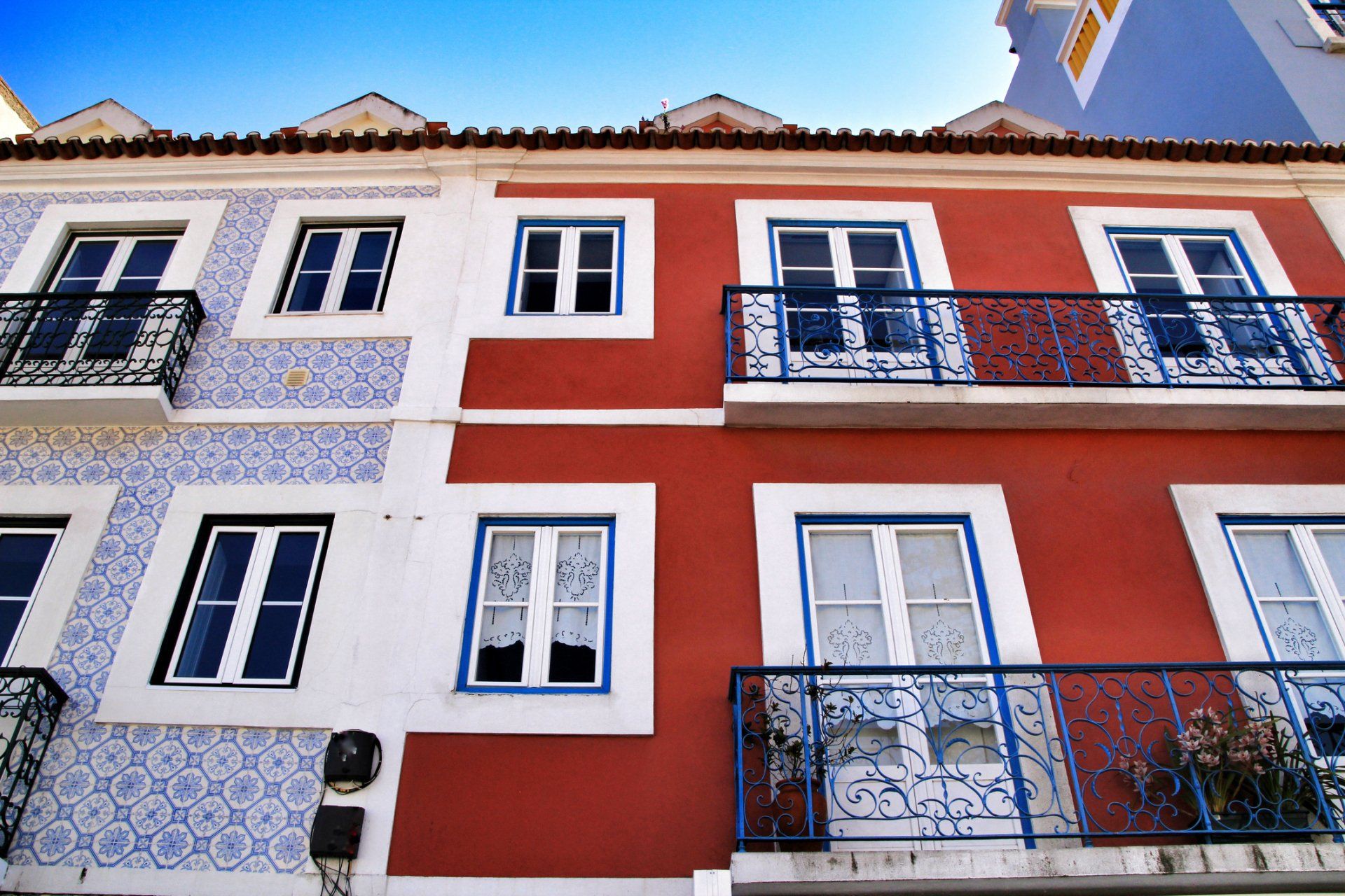 Edificios coloridos con azulejos azules y blancos, pintura roja y balcones ornamentados en Lisboa, Portugal.