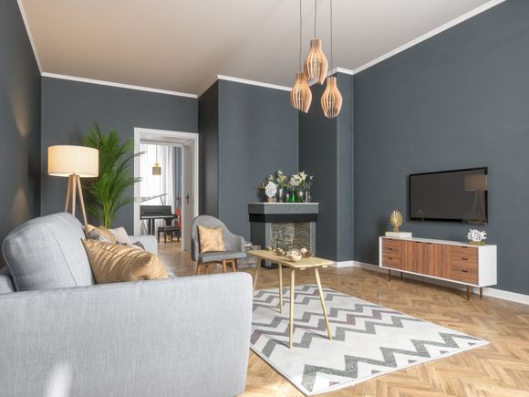 Sala de estar gris con paredes grises, piso de madera, sofá gris y una alfombra.