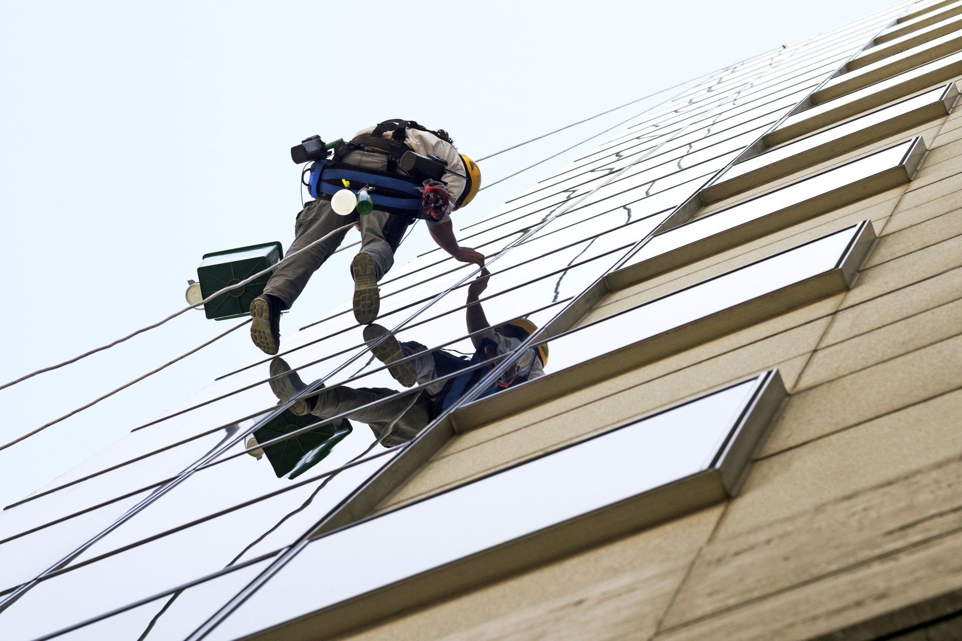 Limpiadores de ventanas en un rascacielos, uno tratando de ayudar al otro.