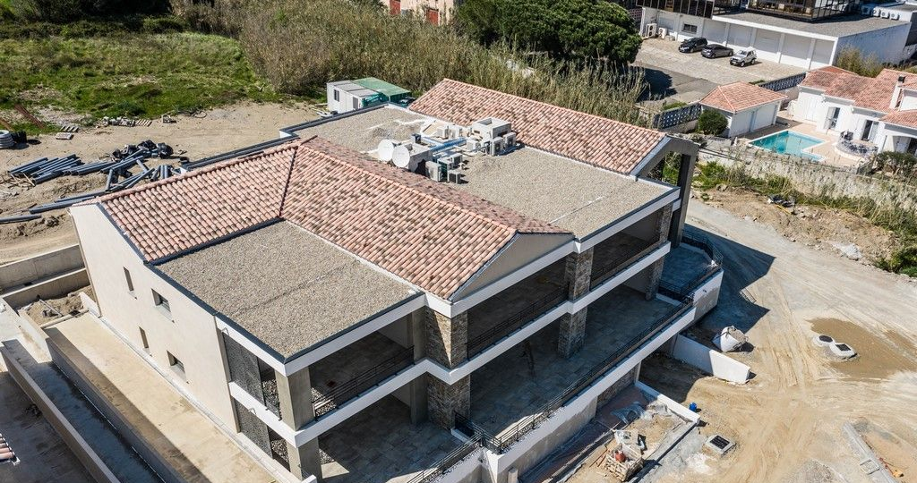Vue aérienne d'un bâtiment en construction avec un toit de tuiles en terre cuite et des murs de couleur claire.