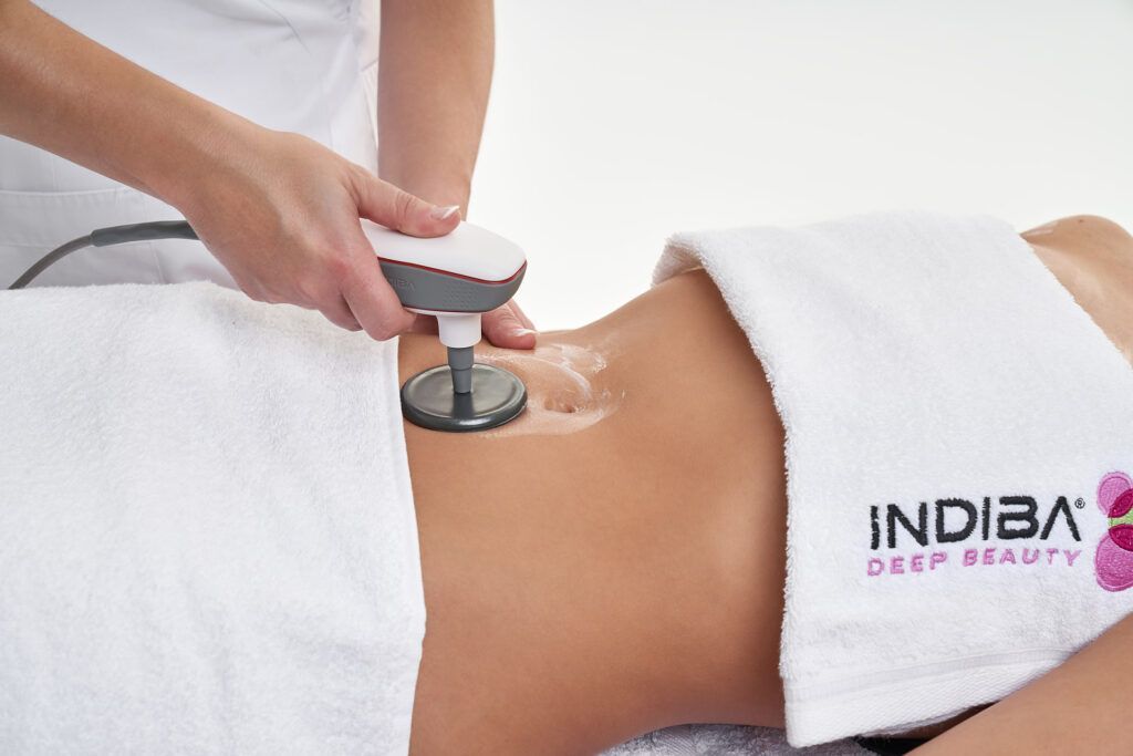 Una mujer está acostada en una cama con una toalla que dice indiba.