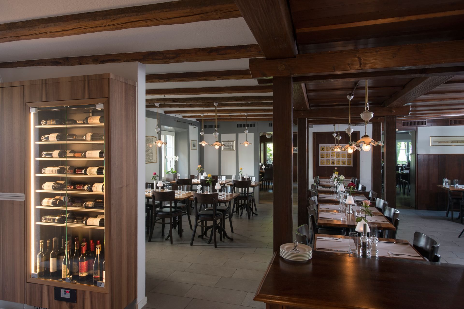 Innenbereich vom Restaurant Pfannenstiel mit Tischen, Stühlen und einem Weinkühlschrank