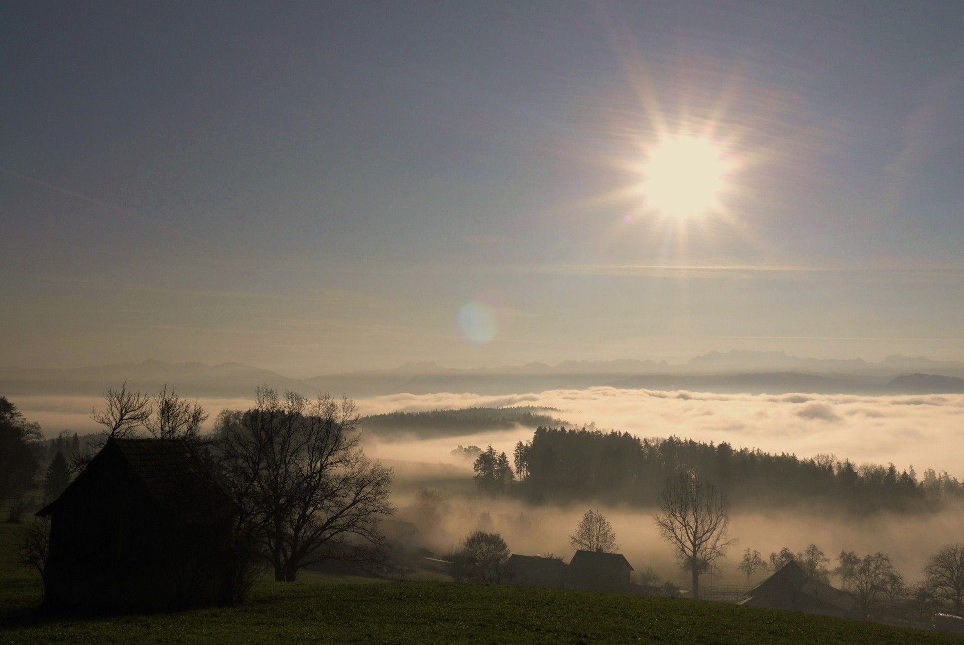 Die Sonne scheint hell über einer nebligen Landschaft. Foto von der Restaurant Pfannenstiel AG.
