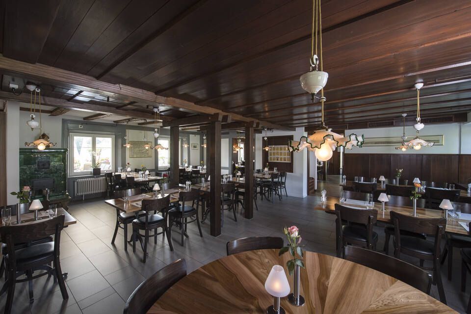 Innenbereich vom Restaurant Pfannenstiel mit Holzbalken, Tischen und Stühlen
