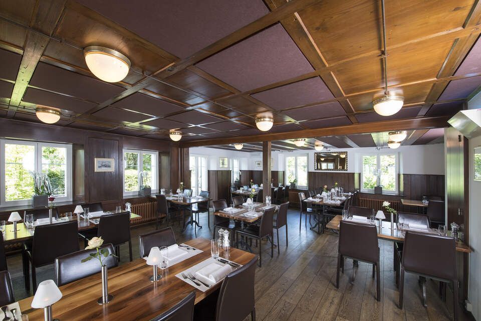 Innenbereich vom Restaurant Pfannenstiel mit Holzbalken, Tischen und Stühlen