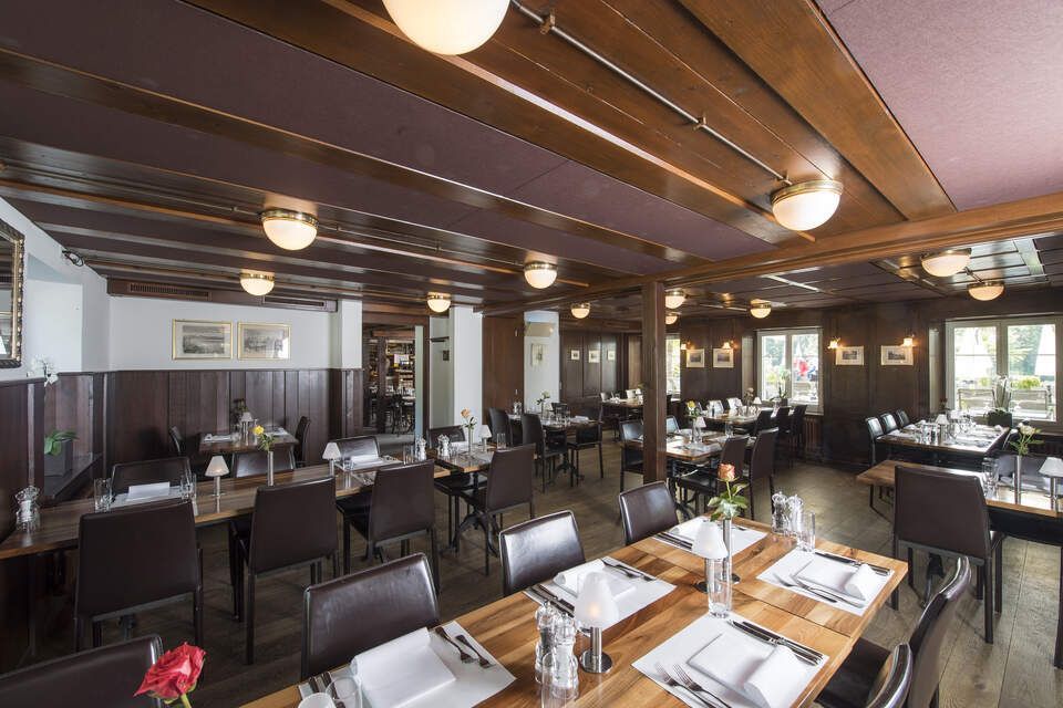 Innenbereich vom Restaurant Pfannenstiel mit Holzbalken, Tischen und Stühlen