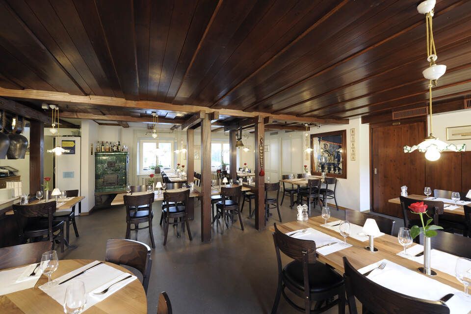Innenbereich vom Restaurant Pfannenstiel mit Holzbalken, Tischen und Stühlen