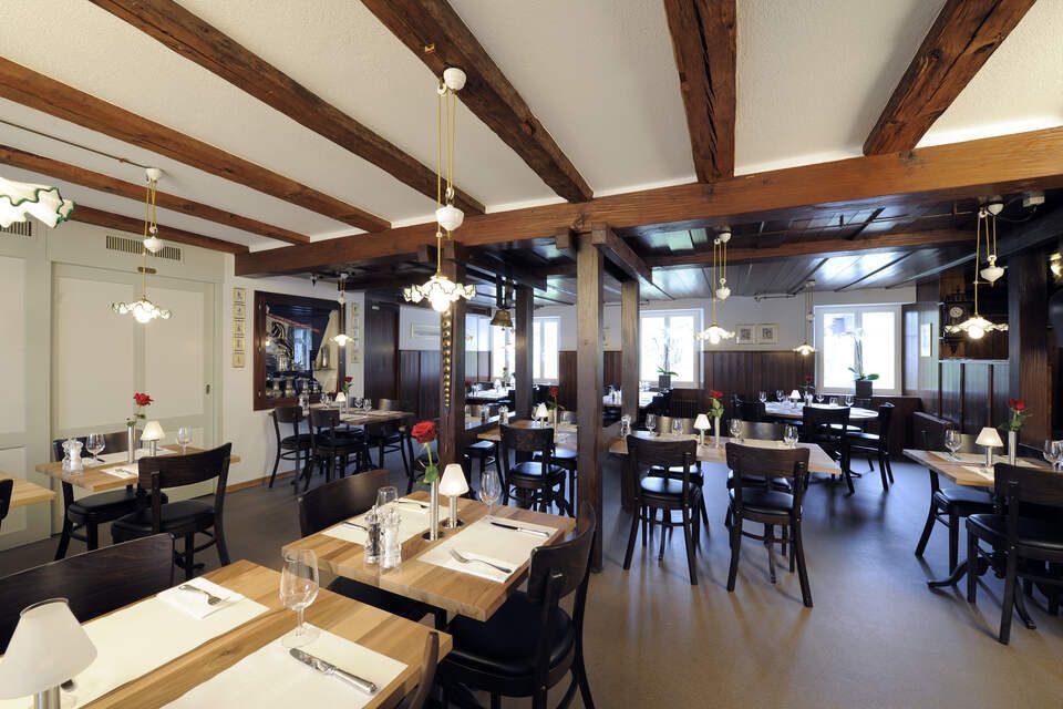 Innenbereich vom Restaurant Pfannenstiel mit Holzbalken, Tischen und Stühlen