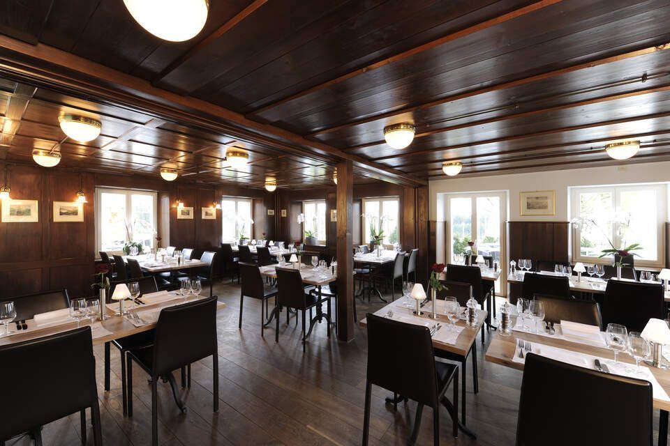 Innenbereich vom Restaurant Pfannenstiel mit Holzbalken, Tischen und Stühlen