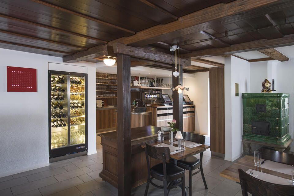 Innenbereich vom Restaurant Pfannenstiel mit Tisch, Stühlen und Weinkühler