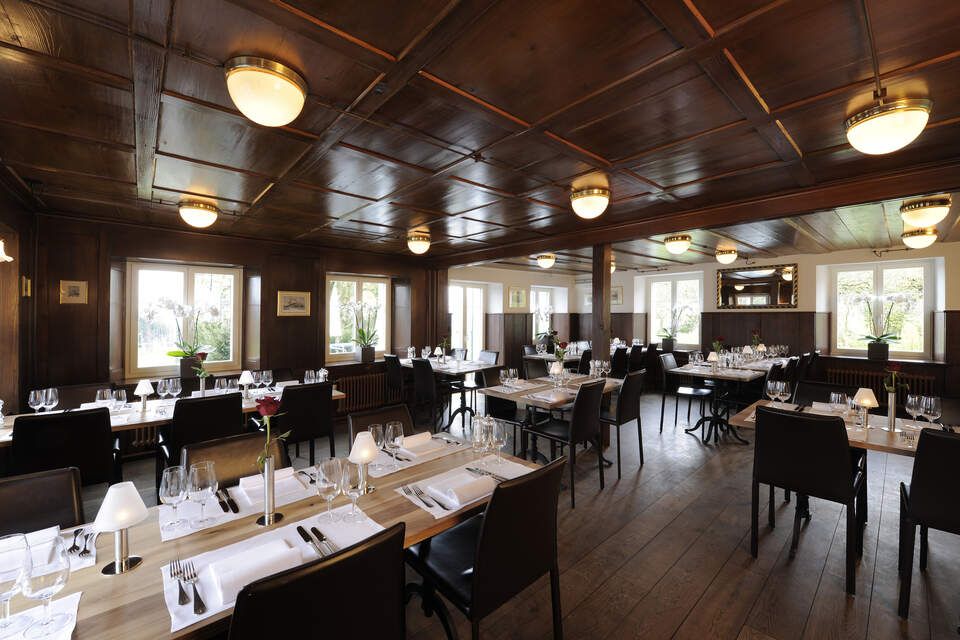 Innenbereich vom Restaurant Pfannenstiel mit Holzbalken, Tischen und Stühlen