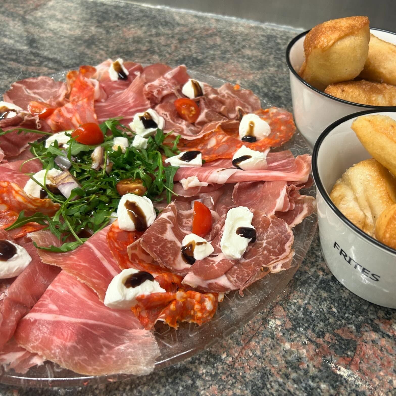 Une assiette de charcuterie avec des petits pains.