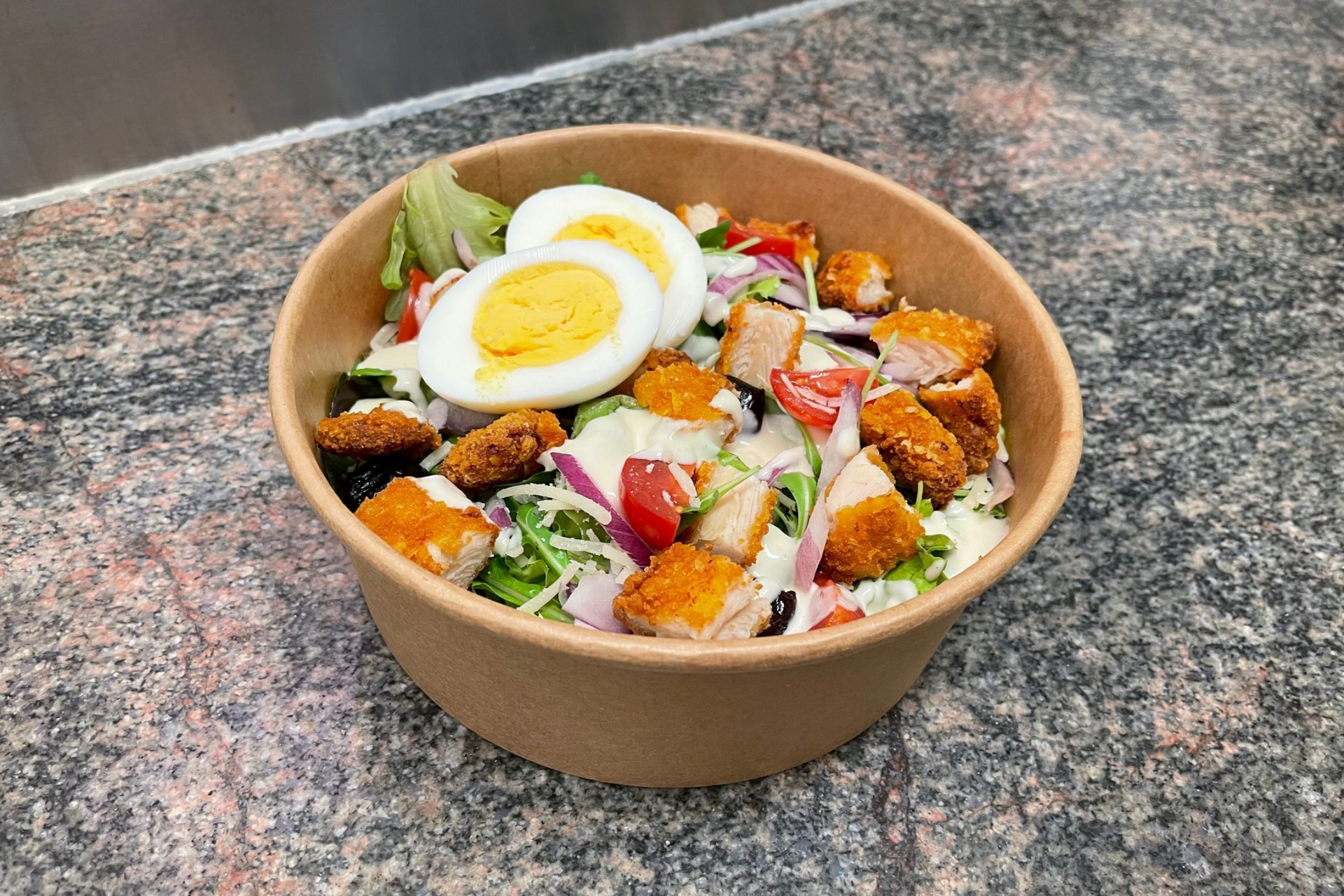 Une salade César dans un conteneur en carton.