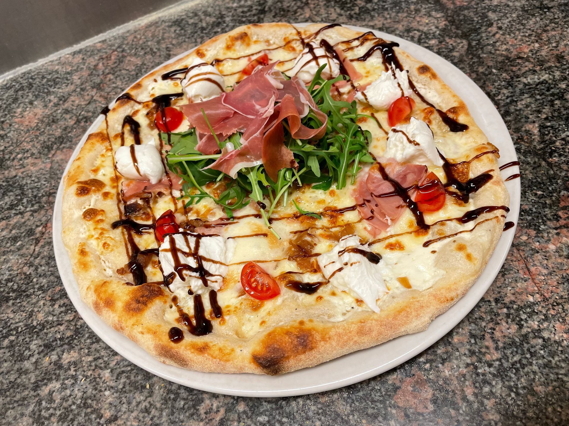 Une pizza garnie de jambon cru et roquette.