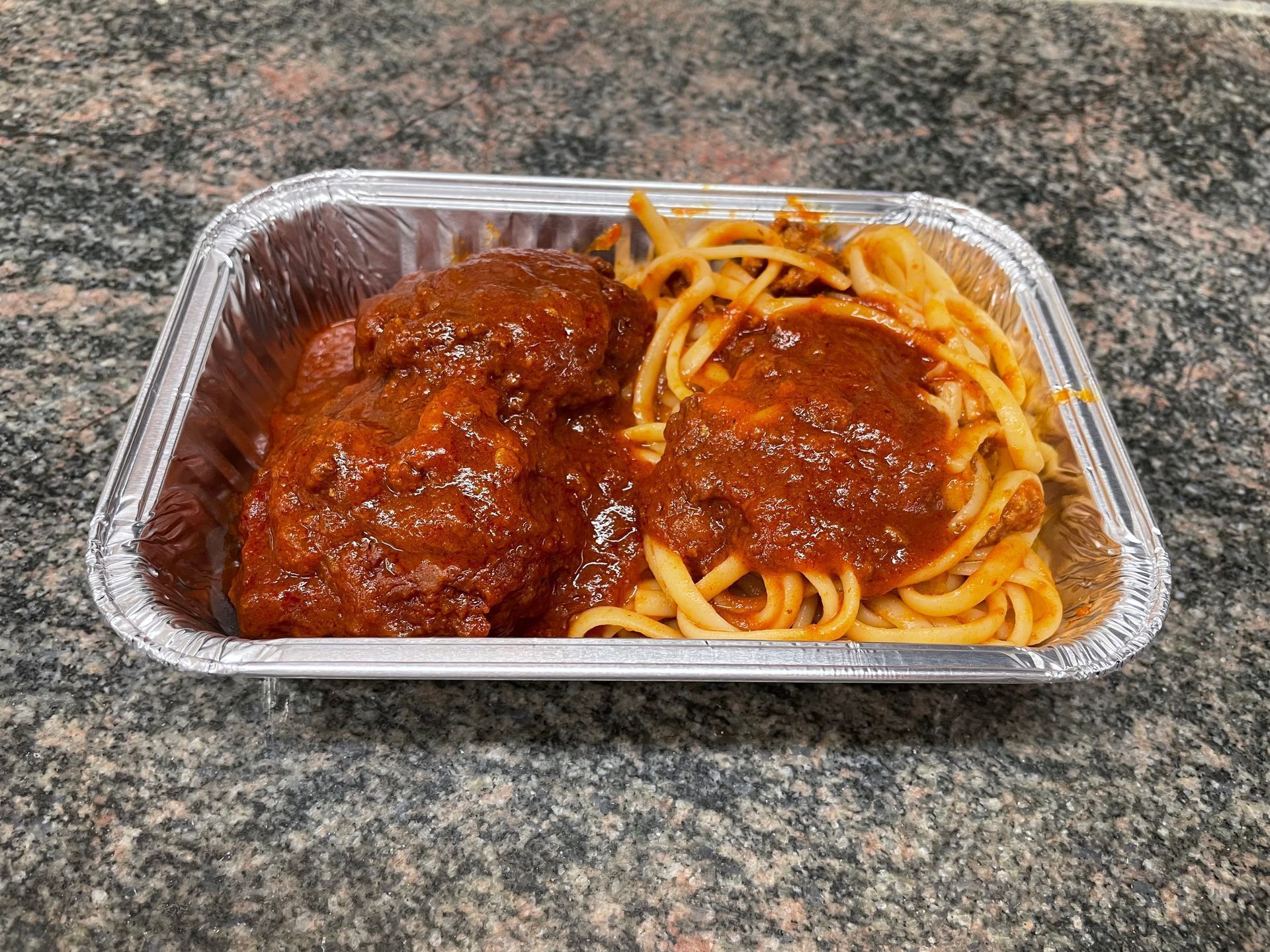 Un plat de spaghetti et boulettes à emporter.